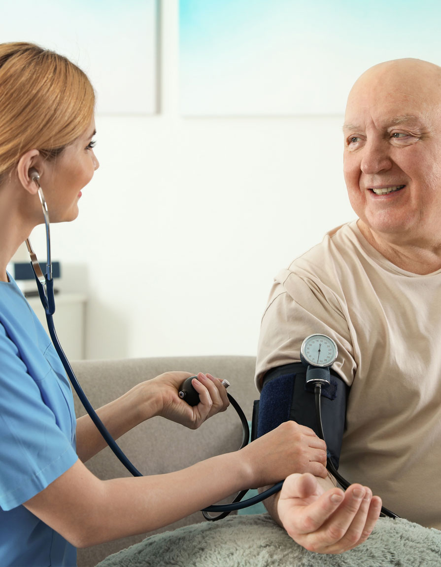 Nurse measuring blood pressure of elderly man indoors